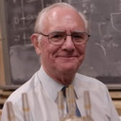 Clayton smiling in front of blackboard